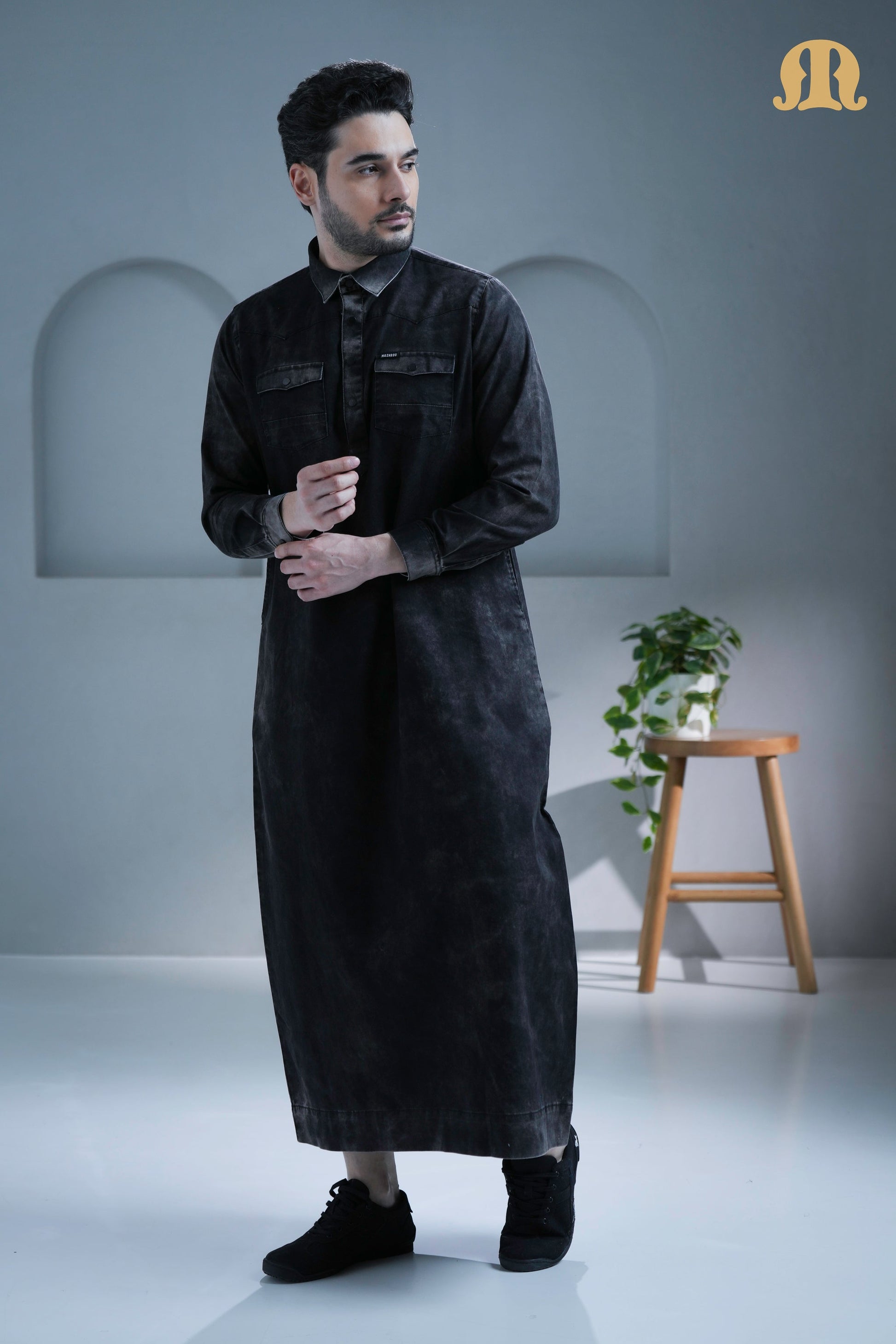 Side profile of the men's black denim thobe from Mashroo, showing its modern cut.